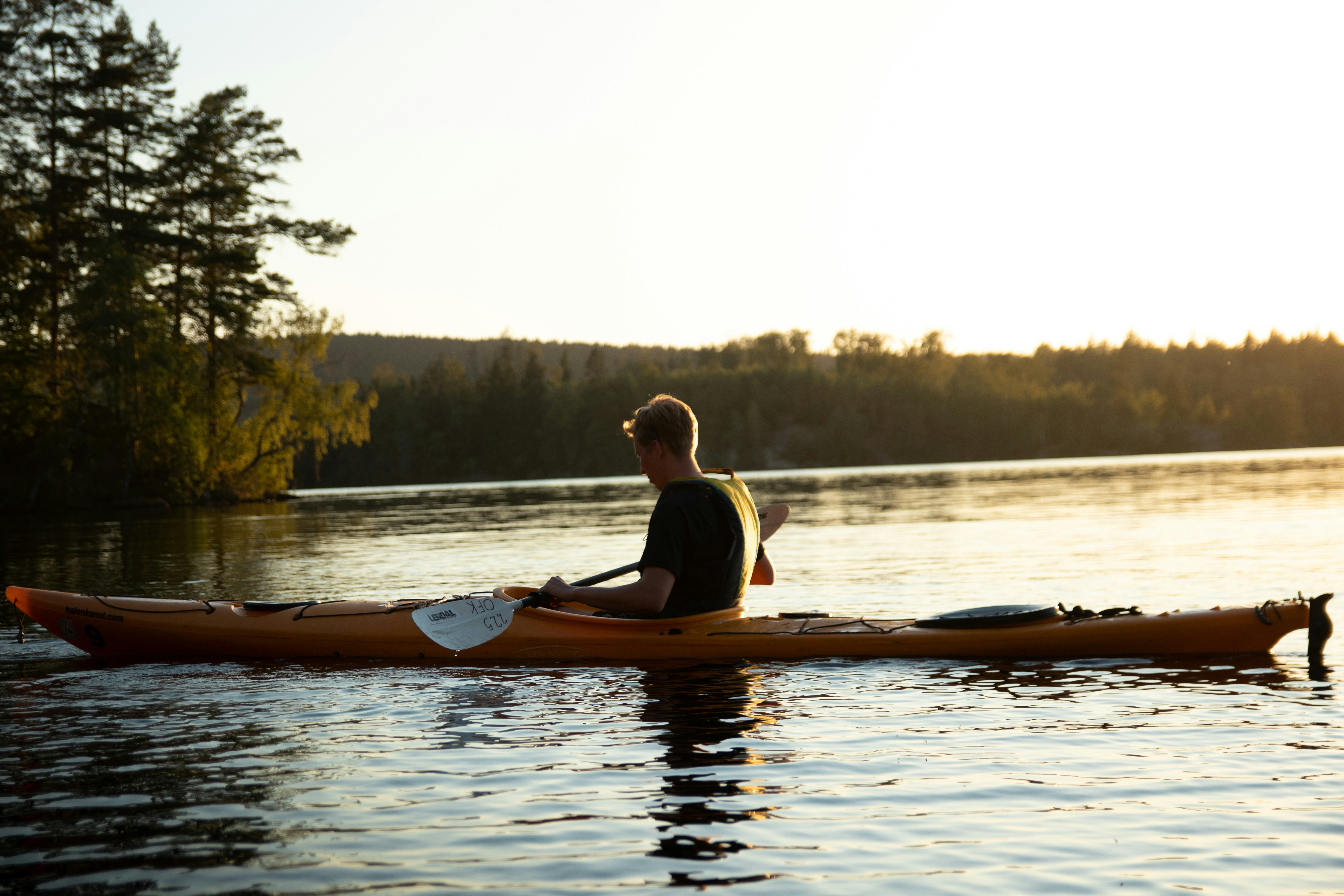 Kayaker paddling on a calm lake at sunset