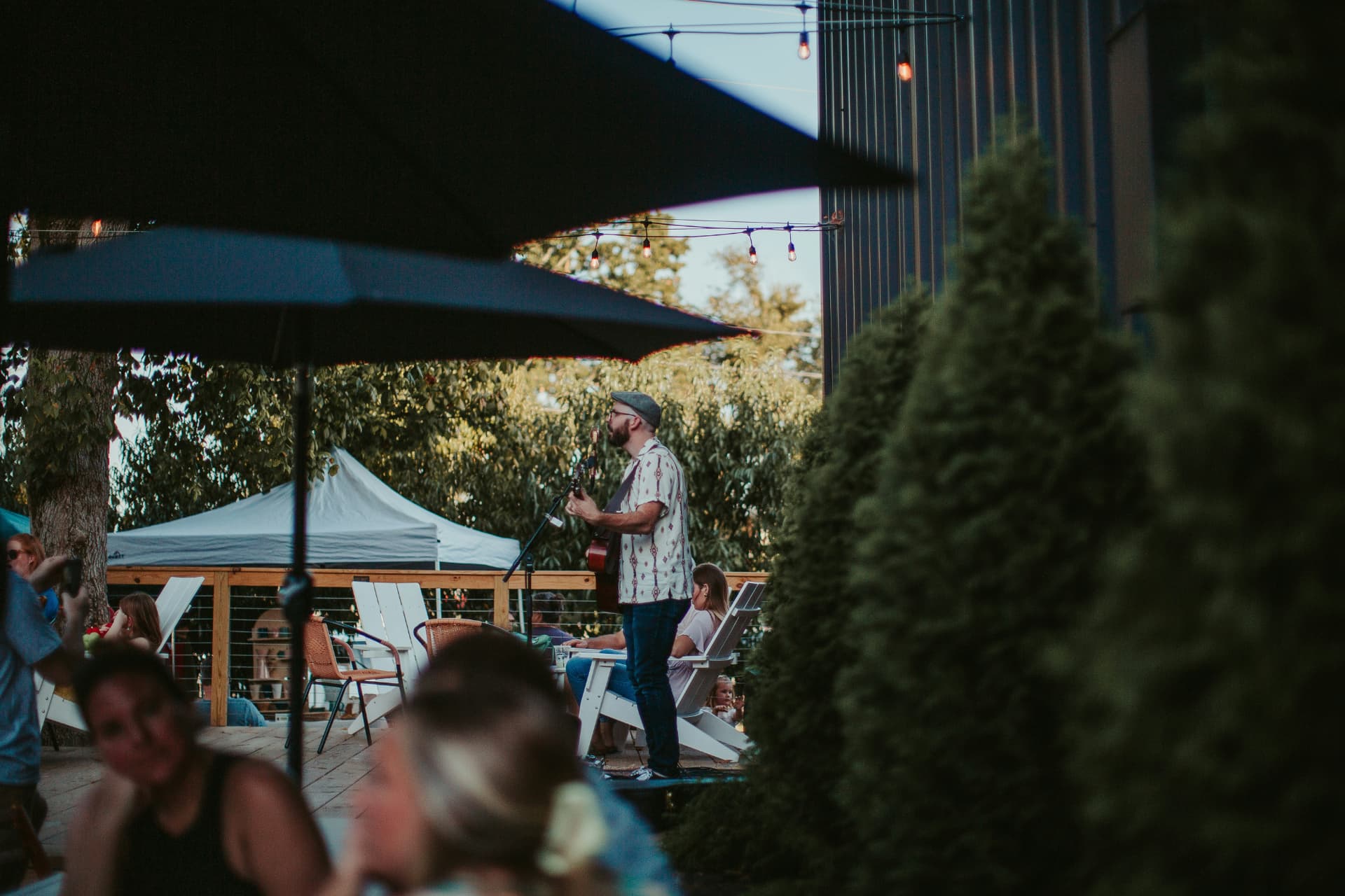 Live music on a patio at golden hour with neighbours gathered under string lights